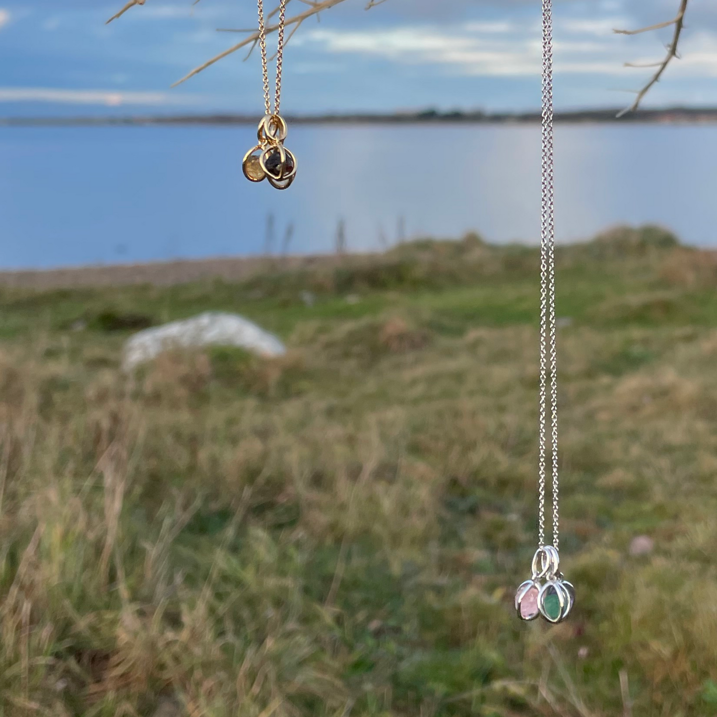 Kombinationer av halsband i guld och silver med hängen med rå kristall på en strand